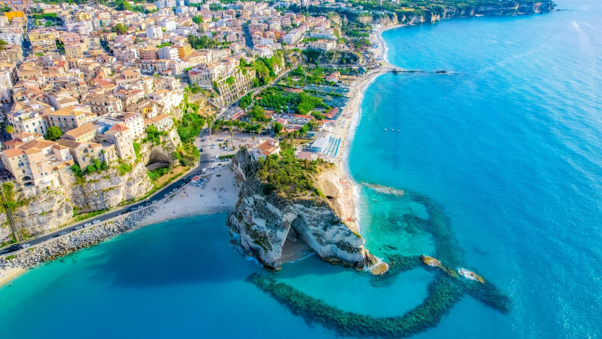 Vista aerea di Tropea, con scogliere, spiagge e mare cristallino.