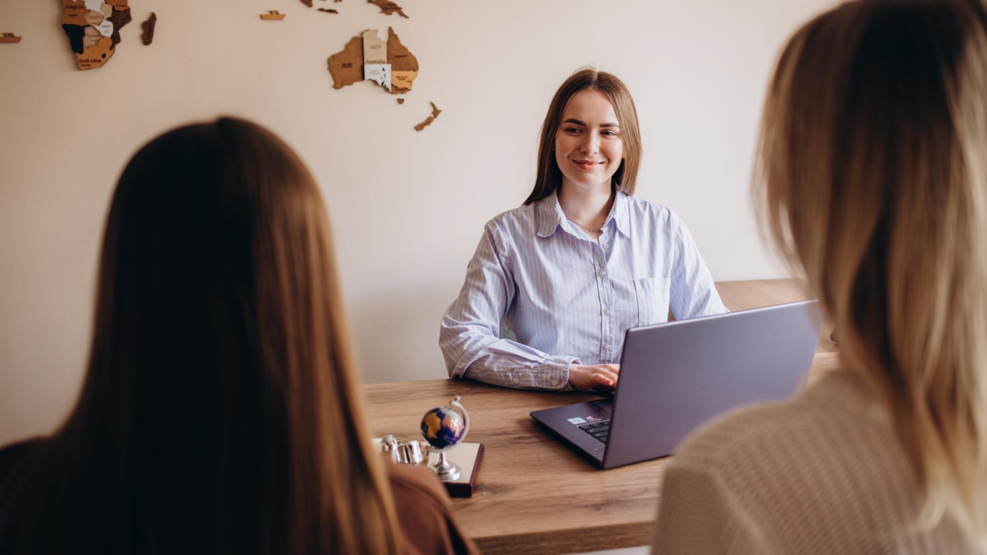 Incontro in ufficio con tre persone, una con laptop e mappa sul muro.