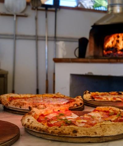 Pizze appena sfornate in un forno a legna, pronte per essere servite.