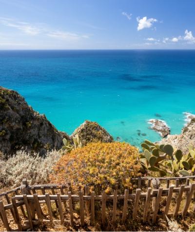 Vista mozzafiato sul mare turchese con vegetazione mediterranea e cielo sereno.