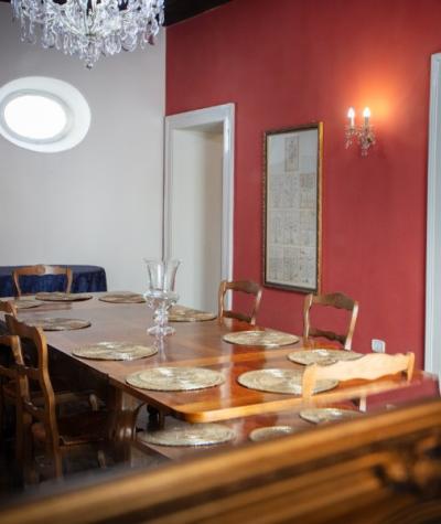 Elegante sala da pranzo con tavolo in legno, piatti dorati e lampadario di cristallo.