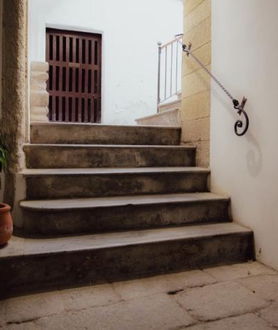 Scala interna in pietra con corrimano in ferro e porta di legno.