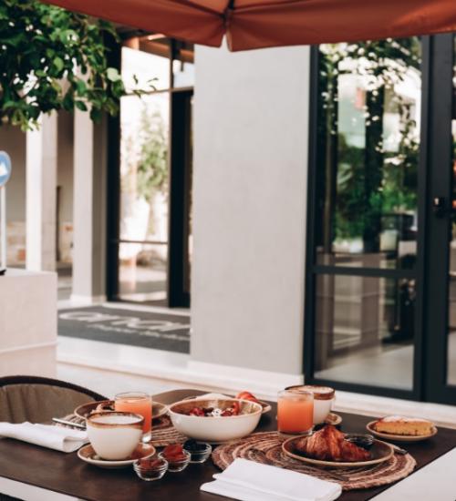 Colazione all'aperto con croissant, caffè e succhi in un ambiente moderno.