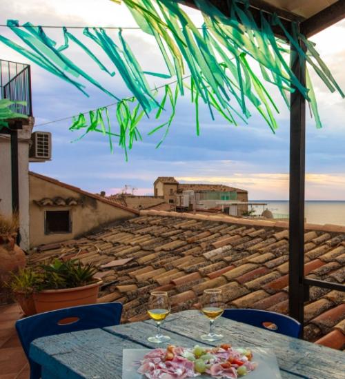 Terrazza con vista mare, tetti in cotto e aperitivo al tramonto.