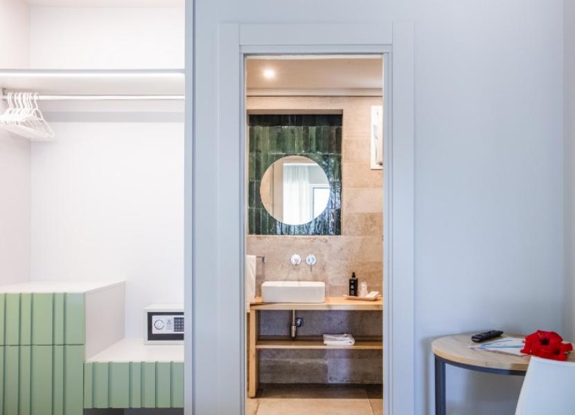 Bagno moderno con lavabo, specchio rotondo e armadio a vista con cassaforte.